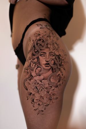 Get mesmerized by this stunning black and gray illustrative tattoo of a Medusa with intricate floral details by Ion Caraman.