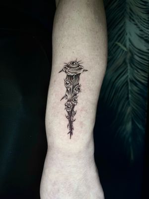Experience the chilling artistry of Claudia Whiteheart with this black-and-gray illustrative tattoo featuring a stake and haunting eyes.