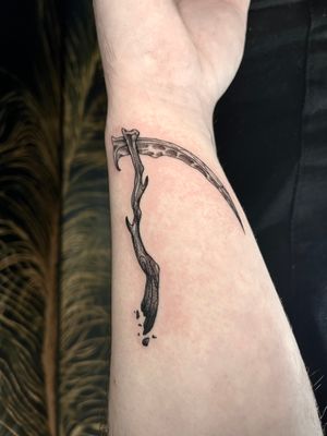 Capture the essence of death with this black and gray illustrative scythe tattoo by Claudia Whiteheart.