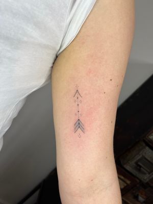 Elegant hand-poked arrow design by Indigo Forever Tattoos, combining fine line technique for a delicate look.