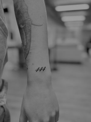 This small lettering tattoo by Ruth Hall features a minimalist design of a number, perfect for those seeking a subtle and meaningful tattoo.