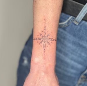 Elegant fine line hand-poked tattoo by Marketa. Exquisite ornamental patterns created with precision and care.