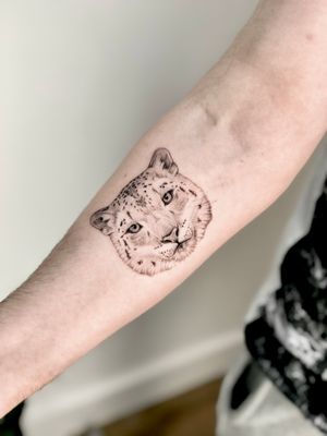 Beautiful black and gray snow leopard tattoo by Sam, showcasing intricate details and realistic features.