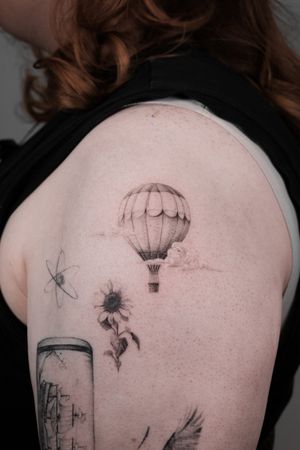 Experience floating among the clouds in this black and gray micro realism tattoo by Viola. A tranquil hot air balloon journey awaits.
