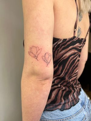 Adorn your skin with a delicate fine line flower design crafted by the talented artist Emma InkBaby. Embrace the beauty of nature in this stunning tattoo.