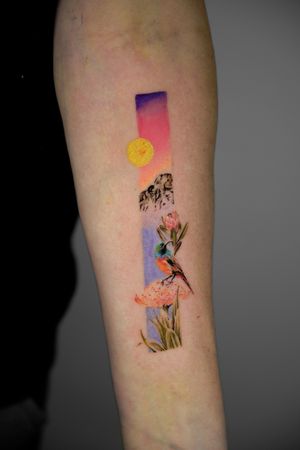 Immerse in the beauty of nature with this colorful illustrative tattoo featuring a scenic mountain, hummingbird, flowers, and a delicate frame by tattoo artist Viola.