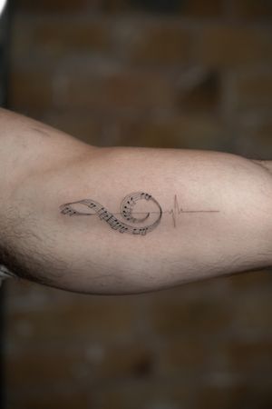Elegant and intricate fine line tattoo of a treble clef symbolizing love for music, created by Viola.