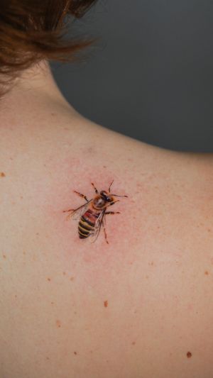 Experience the intricate details of a lifelike bee in this stunning micro realism tattoo by artist Viola.