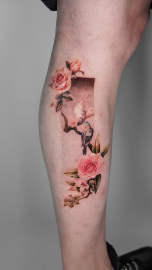 This stunning micro realism tattoo features a bird, flower, rose, frame, and branch in vibrant colors, expertly executed by the talented artist Viola.