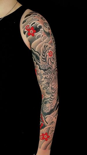 Experience the power and beauty of a Japanese tiger and sakura tattoo by renowned artist Martin Kirke. Embrace the traditional artwork and symbolism of this stunning design.