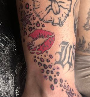 Unique tattoo featuring a skull with lipstick, lips, kiss, and animal pattern by Zanzi La Vey. A bold and edgy design.