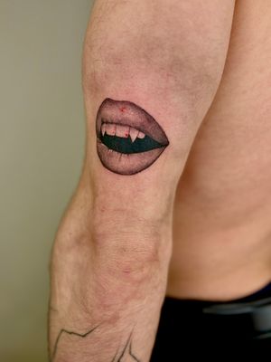 Experience the seduction with this black and gray micro realism tattoo of vampire lips by Ruth Hall.