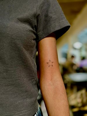 A fine line tattoo of a delicate star design by talented artist Ruth Hall, perfect for those seeking a subtle yet beautiful piece of body art.