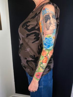 Experience the beauty of nature with this stunning realistic tattoo by Marie Terry, featuring a bird, rose, and family picture.