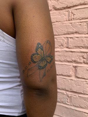 Beautiful small lettering butterfly tattoo on dark skin, adorned with a meaningful bow and ribbon. By jadeshaw_tattoos.