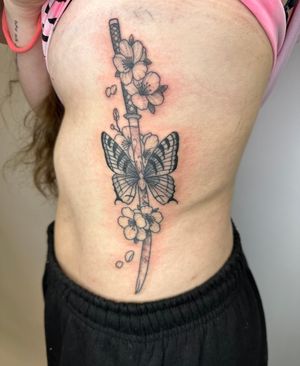 Unique tattoo design combining delicate butterfly and flower with powerful sword and katana motifs by jadeshaw_tattoos.