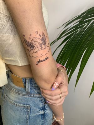 Get a heavenly touch with this delicate cherub and clouds design by jadeshaw_tattoos. Perfect for those who love small lettering and illustrative tattoos.