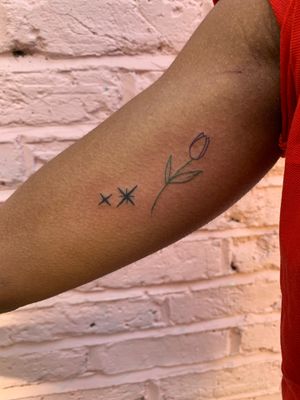 Elegant fine line illustration combining a star and tulip in vibrant colors on dark skin by jadeshaw_tattoos.