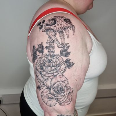 A stunning black and gray tattoo combining a skull and flower motif, expertly executed by Belle Tannahill. Perfect for an edgy yet elegant look.