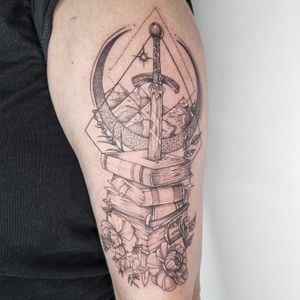 Experience the magic of dotwork and illustrative style in this tattoo by Belle Tannahill. Featuring a mystical mountain, flower, sword, and book scenery.