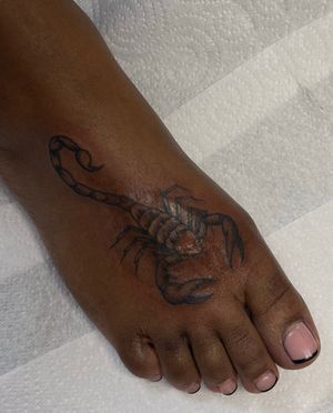 Get an illustrative scorpion tattoo on dark skin by the talented artist Julia Bertholdi. Unique, bold, and striking design.