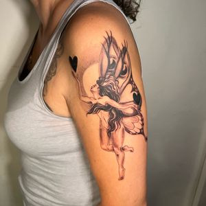 Illustrative black and gray tattoo of a elegant fairy with wings holding a heart, beautifully executed by artist Cristina.
