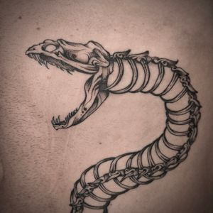 Discover the mesmerizing fusion of a snake and skeleton in this stunning illustrative tattoo by artist Jenny Dubet.