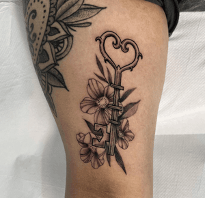 Elegant dotwork illustration combining a delicate flower and intricate key design, expertly executed by tattoo artist Cristina.