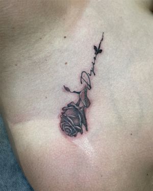 A single stem rose black and grey rose with my clients daughters name just under the collar bone 