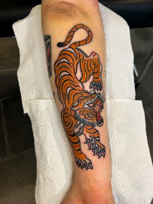 Roar with this fierce tiger tattoo in classic traditional style, expertly done by the talented artist Barney Coles. Make a statement with this timeless design.