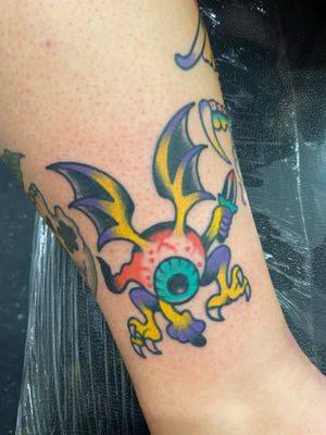 Colour traditional tattoo of a flying eyeball with a dagger 