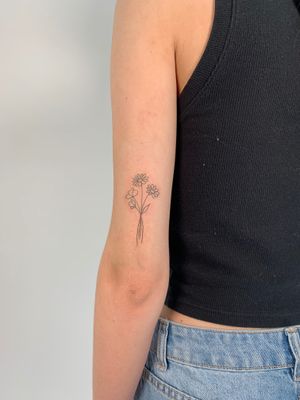 Get a delicate and elegant fine line tattoo of a flower bundle by Chloe Hartland. This minimalistic design is perfect for those who appreciate subtlety and beauty in their ink.