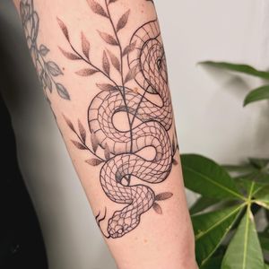Illustrative dotwork tattoo by Michelle Harrison featuring a snake intertwined with a branch, plant, and vine motif.