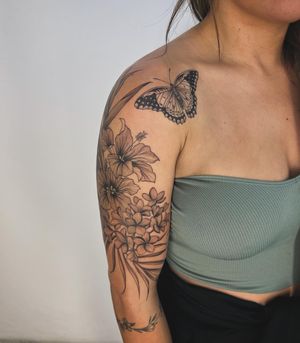 Capture the beauty of nature with this stunning floral tattoo featuring a butterfly and flower, expertly designed by the talented artist Paula.