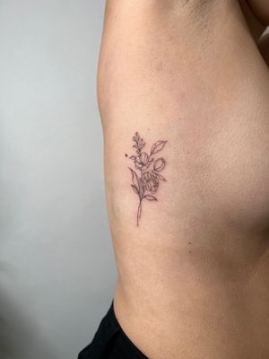 Elegant and intricate fine line tattoo of a delicate flower bouquet by Emma InkBaby.