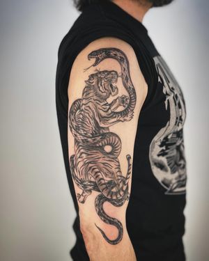 Get a unique and fierce tattoo featuring a snake and tiger design, expertly done by tattoo artist Paula in an illustrative style.