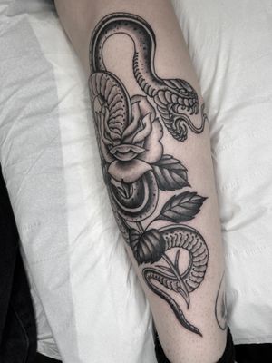 Experience the timeless artistry of Barney Coles with this striking traditional tattoo featuring a dynamic snake and delicate flower motif.