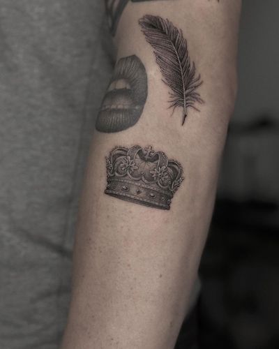Experience the intricacy of micro-realism with this black and gray tattoo featuring a feather, crown, lips, and patchwork design by HellHabits.