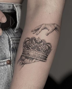 Black and gray micro realism tattoo featuring a crown held by hands, by HellHabits.