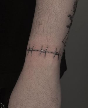 Experience the sharp beauty of barbed wire in this black and gray micro realism tattoo by HellHabits.