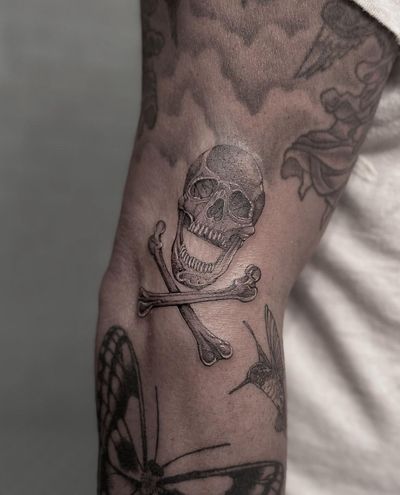 Captivating black and gray illustrative tattoo by HellHabits, featuring a menacing pirate skull with crossed bones.