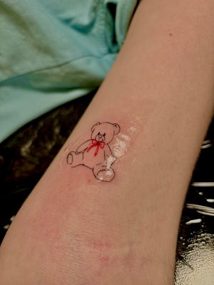 Discover the charm of this intricate fine line tattoo featuring a delicate teddy bear design, expertly crafted by tattoo artist Ruth Hall.