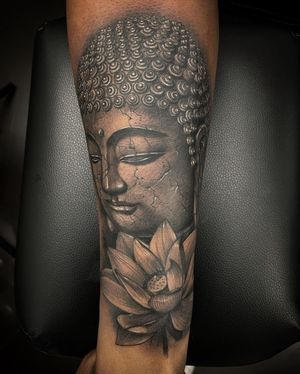 Elegant black and gray tattoo of a Buddha statue with lotus flowers, created by Simon Says Ink.