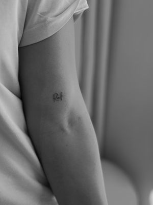 This delicate tattoo features small lettering done in a fine line style by the talented artist Timmy, perfect for those wanting a subtle yet striking design.