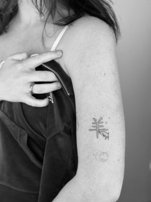 Get inked with a unique fine line tattoo featuring a goat and kanji lettering by the talented artist Timmy.