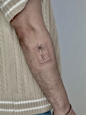 Capture the essence of the beach with this illustrative palm tree stamp tattoo by Katerina Nireta.