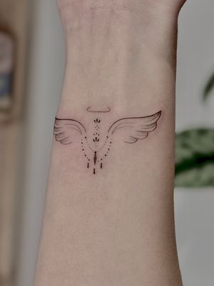 Elegantly crafted fine line and ornamental tattoo featuring intricate angel wings by the talented artist Katerina Nireta.