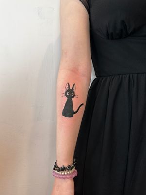 Capture the magic of Studio Ghibli with this adorable anime-style tattoo of Jiji the cat by renowned artist Oliver Soames.