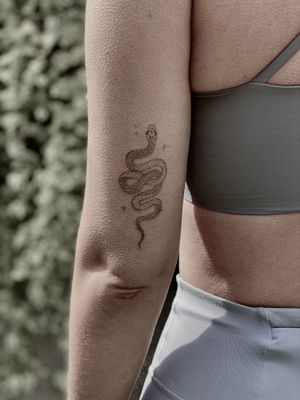 Elegant and dainty snake tattoo by Katerina Nireta, combining fine line work with illustrative style for a unique look.