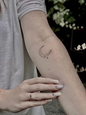 Elegant fine line tattoo featuring a delicate moon and star motif by Katerina Nireta.